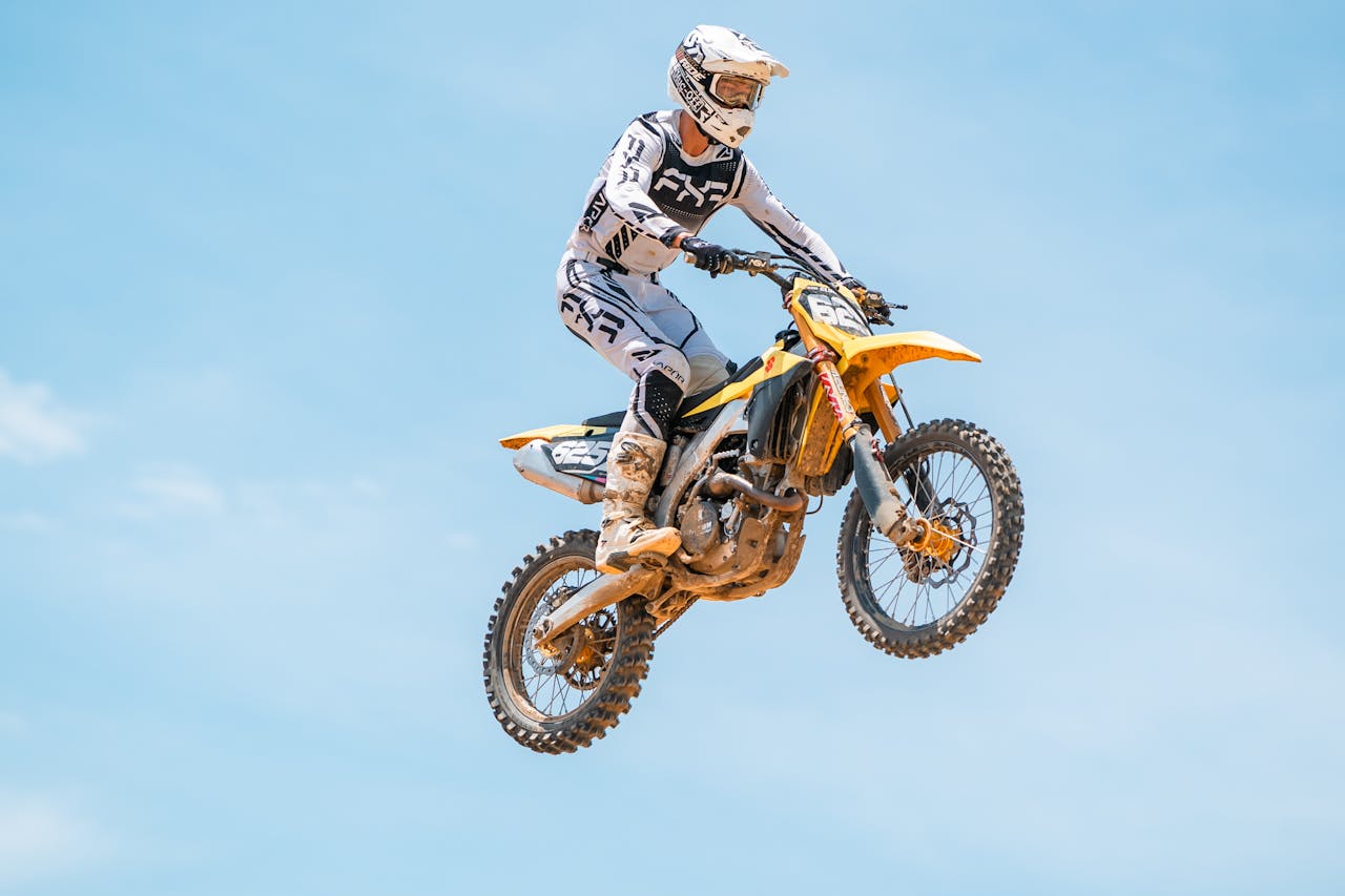 Dynamic shot of a motocross rider performing a jump under a clear blue sky, showcasing action and skill.